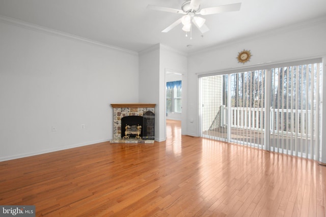 unfurnished living room featuring crown molding, a stone fireplace, light wood-style flooring, baseboards, and ceiling fan