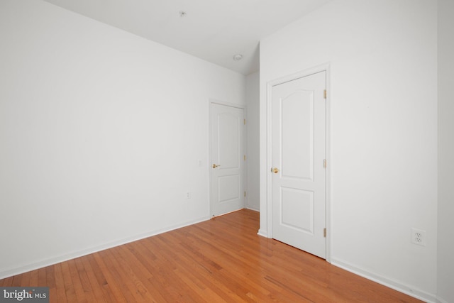 spare room featuring baseboards and light wood finished floors