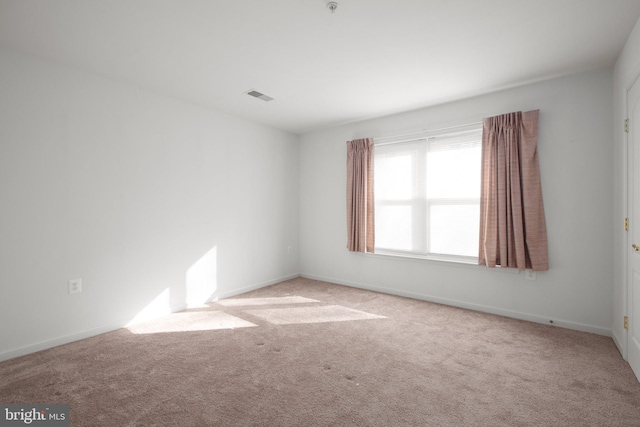 carpeted empty room featuring baseboards and visible vents