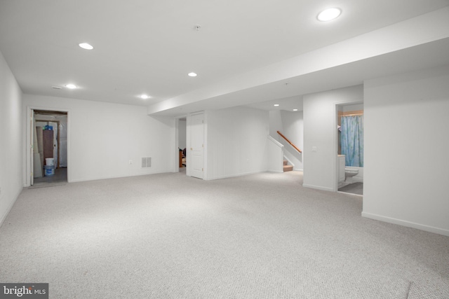 finished basement with stairs, visible vents, carpet floors, and recessed lighting