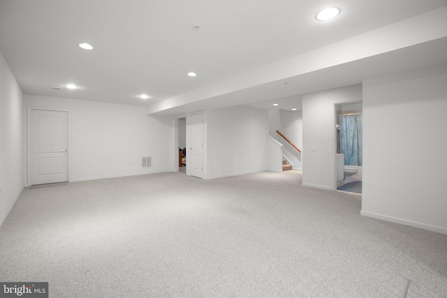 finished basement featuring stairs, visible vents, recessed lighting, and carpet