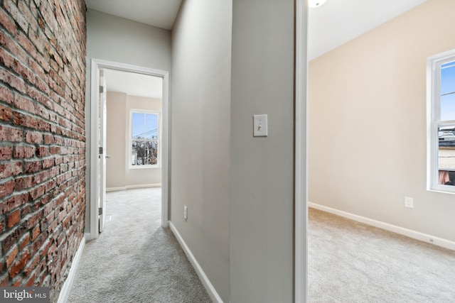 corridor with brick wall, baseboards, and carpet floors