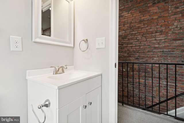 bathroom with vanity and brick wall