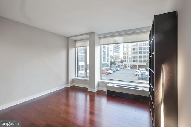spare room with baseboards and hardwood / wood-style floors