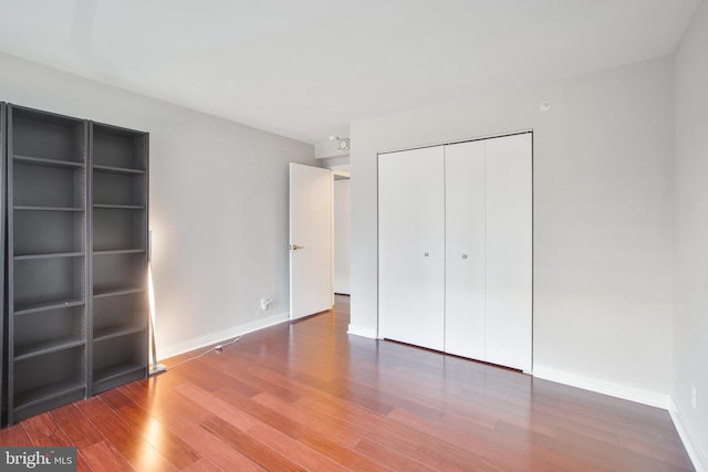 unfurnished bedroom featuring baseboards, a closet, and wood finished floors