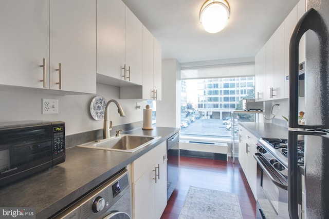 kitchen featuring dark wood-style flooring, washer / clothes dryer, a sink, black appliances, and white cabinetry