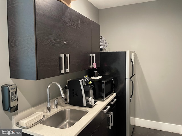 kitchen with black microwave, tile patterned flooring, light countertops, baseboards, and a sink