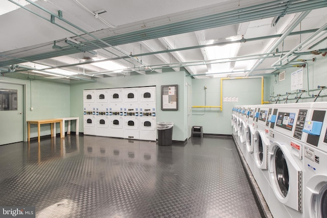 common laundry area with baseboards, tile patterned floors, stacked washer / dryer, and washing machine and clothes dryer