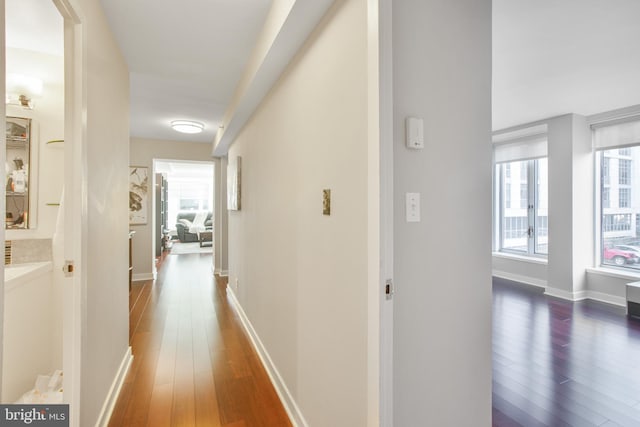 corridor with baseboards and hardwood / wood-style floors
