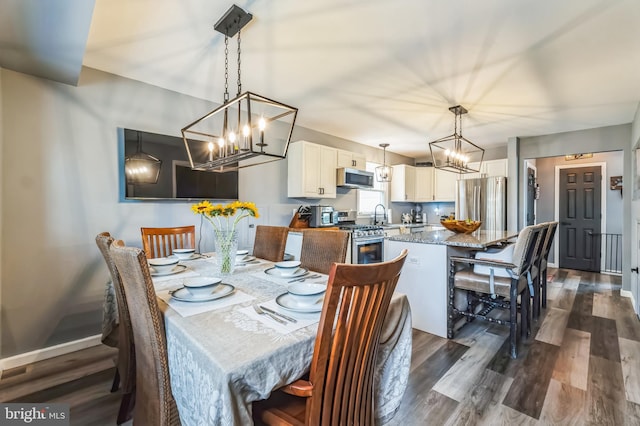 dining space featuring dark wood-style floors, a notable chandelier, and baseboards