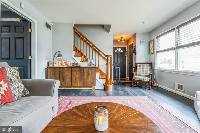 foyer featuring baseboards, visible vents, wood finished floors, and stairway