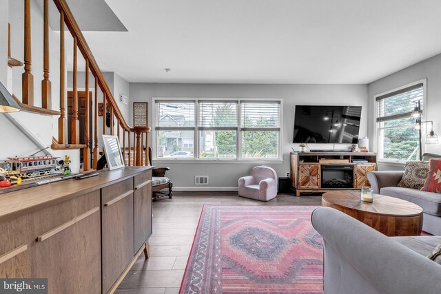 living area with stairs, visible vents, wood finished floors, and a wealth of natural light