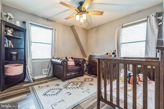 bedroom featuring baseboards, visible vents, wood finished floors, and a ceiling fan