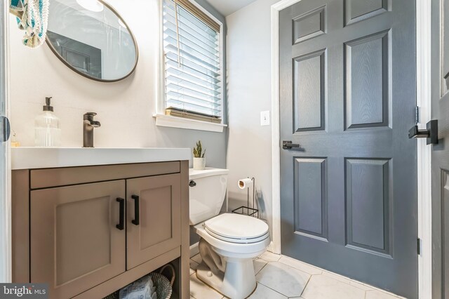 half bath with tile patterned floors, toilet, and vanity