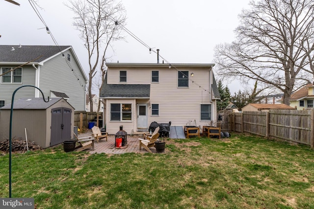 rear view of house with a patio, a fire pit, a lawn, and a shed