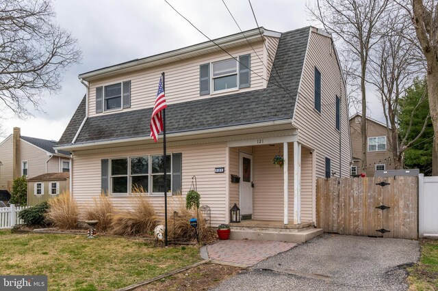 view of front of property with a gambrel roof, a gate, fence, a front lawn, and a shingled roof