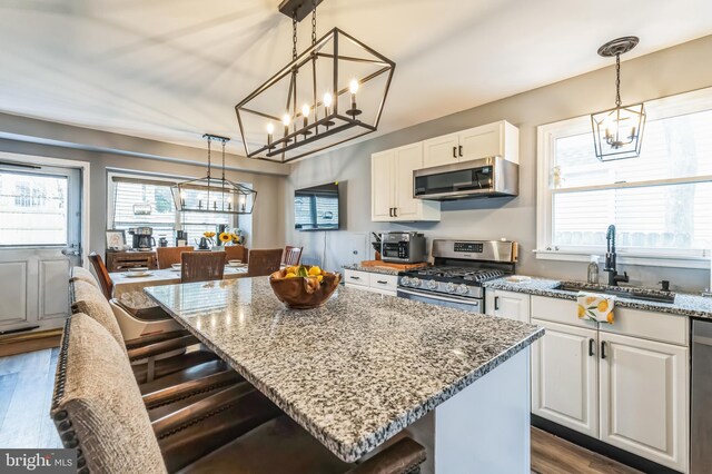 kitchen with white cabinetry, an inviting chandelier, a sink, and stainless steel appliances