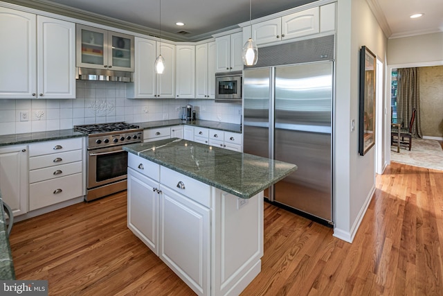 kitchen with built in appliances, ornamental molding, light wood-style flooring, baseboards, and backsplash