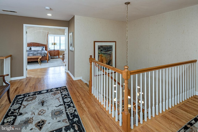 corridor featuring wood finished floors, an upstairs landing, and baseboards