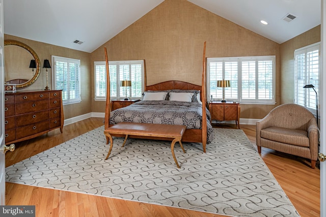 bedroom featuring wood finished floors, baseboards, wallpapered walls, and high vaulted ceiling