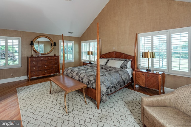 bedroom with wood finished floors, vaulted ceiling, baseboards, and wallpapered walls