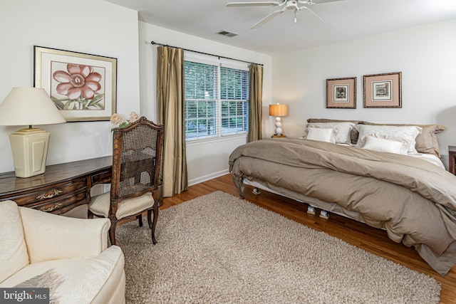 bedroom featuring wood finished floors, a desk, baseboards, and a ceiling fan
