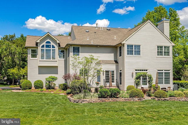 rear view of property with a lawn, a chimney, central air condition unit, and a shingled roof