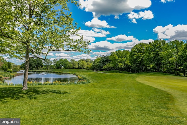 view of home's community with a water view, view of golf course, and a yard