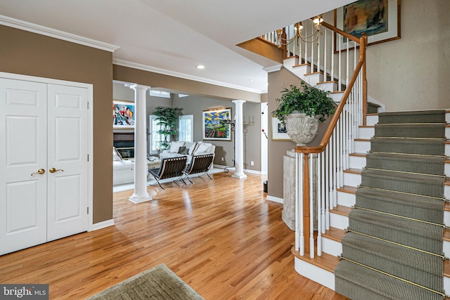 stairs featuring decorative columns, ornamental molding, wood finished floors, baseboards, and recessed lighting