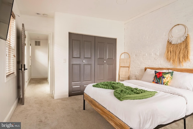 bedroom with light colored carpet, visible vents, a closet, and baseboards
