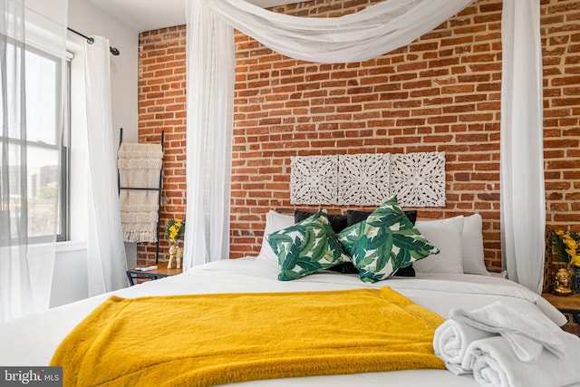 bedroom featuring multiple windows and brick wall