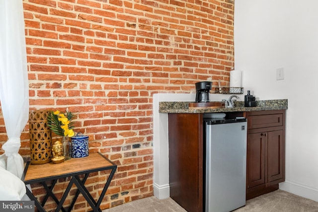 bar with freestanding refrigerator, wet bar, light carpet, and baseboards