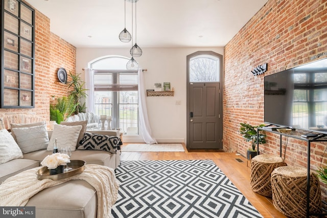 foyer featuring baseboards, brick wall, and light wood finished floors