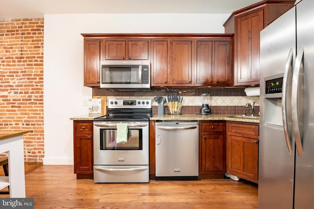 kitchen featuring tasteful backsplash, light wood-style flooring, and appliances with stainless steel finishes