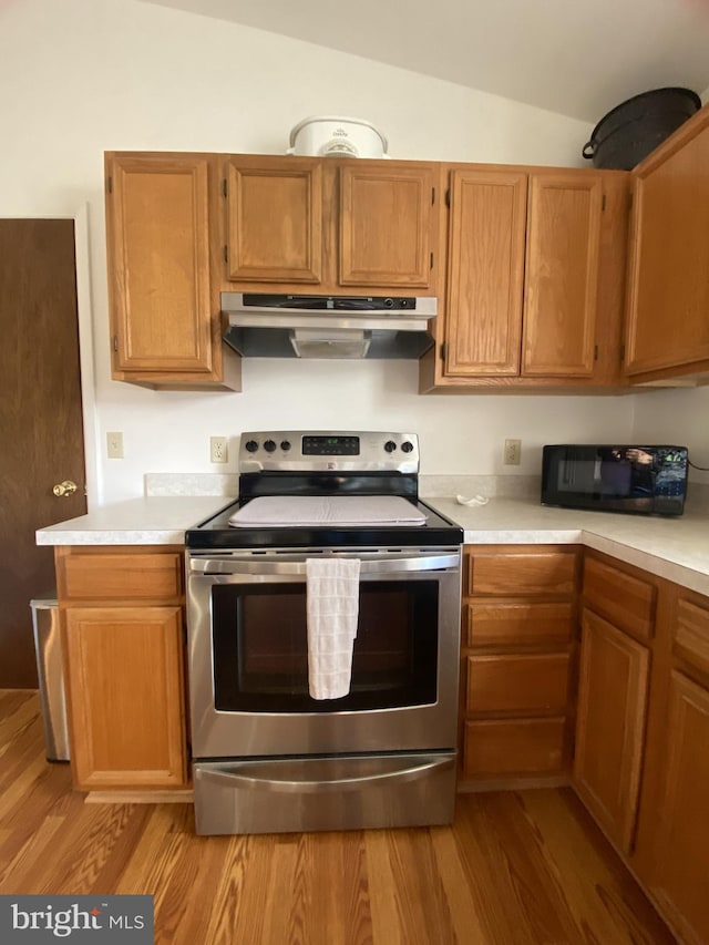 kitchen featuring stainless steel electric range oven, under cabinet range hood, light countertops, black microwave, and lofted ceiling