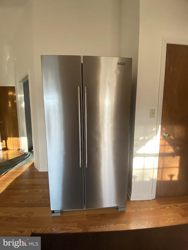 interior details with baseboards, wood finished floors, and high end fridge