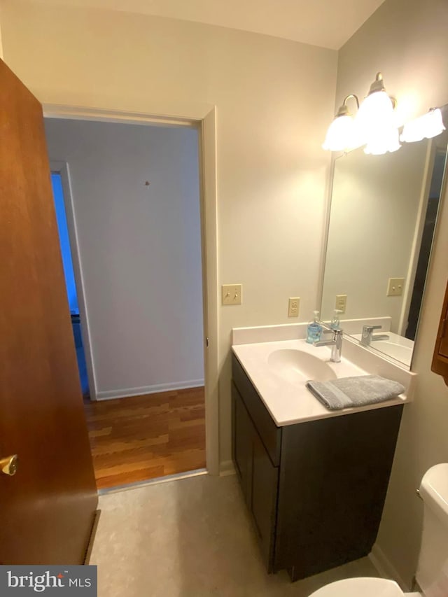 bathroom featuring toilet, wood finished floors, and vanity
