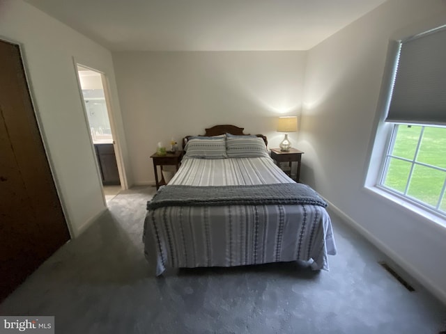 carpeted bedroom featuring visible vents, connected bathroom, and baseboards
