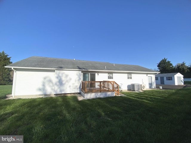 rear view of property featuring a lawn, an outdoor structure, central AC, and a wooden deck