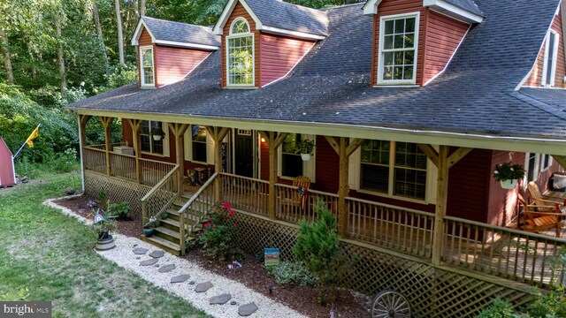 view of front of property featuring a front yard, a shingled roof, and covered porch