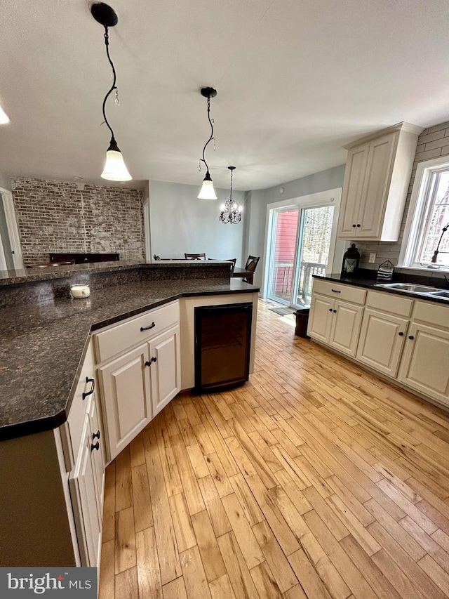 kitchen with light wood finished floors, dark countertops, a sink, and a healthy amount of sunlight