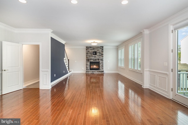 unfurnished living room with a fireplace, wood finished floors, stairs, and ornamental molding