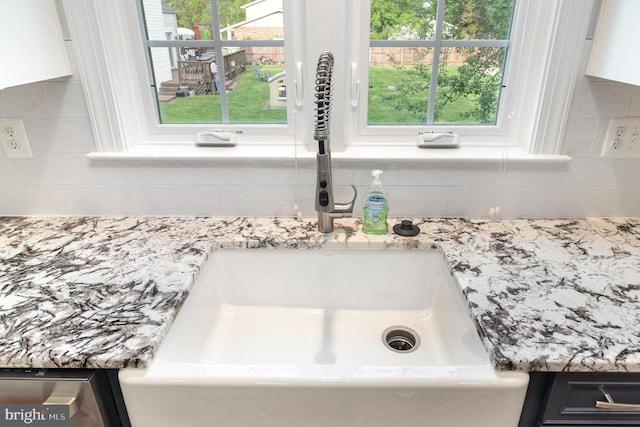 room details with white cabinets, a sink, and tasteful backsplash