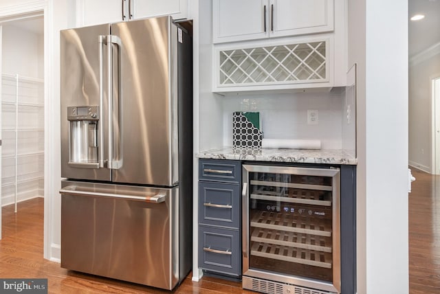 bar featuring a bar, beverage cooler, high quality fridge, dark wood finished floors, and ornamental molding