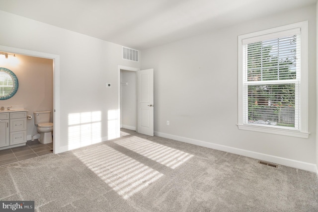 unfurnished bedroom with connected bathroom, carpet floors, visible vents, and baseboards