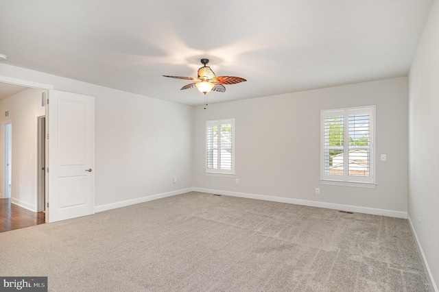spare room featuring ceiling fan, baseboards, and light colored carpet
