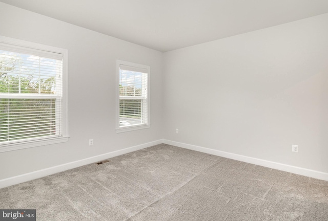 carpeted spare room with baseboards and visible vents