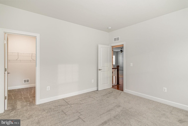 unfurnished bedroom with a spacious closet, carpet flooring, and visible vents