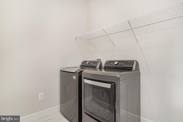 laundry room featuring washing machine and dryer, baseboards, marble finish floor, and laundry area
