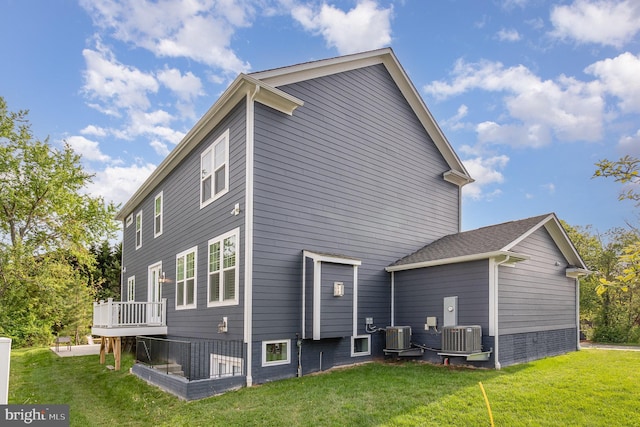 rear view of property featuring a lawn, a wooden deck, and central AC